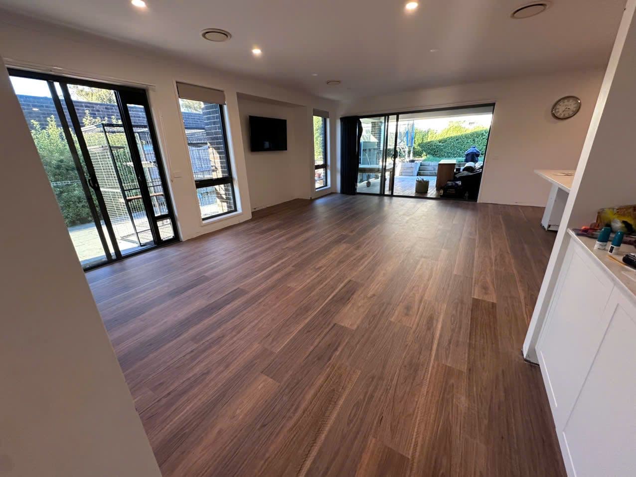 The open-plan living zone with walnut-toned boards running unbroken to the alfresco.