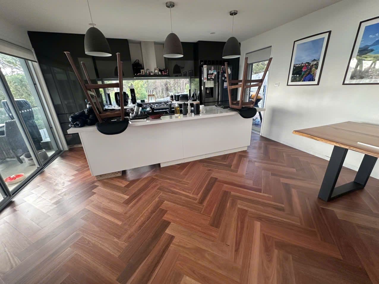 Herringbone timber continuing through the kitchen, stools upturned on the island.